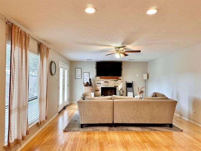 5103 Kleinbrook Dr, Houston, TX 77066 - living room with a textured ceiling, ceiling fan, light wood-style flooring, and a fireplace