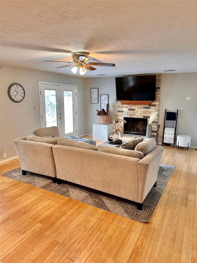 5103 Kleinbrook Dr, Houston, TX 77066 - living room featuring a textured ceiling, a fireplace, light wood-style flooring, and a ceiling fan