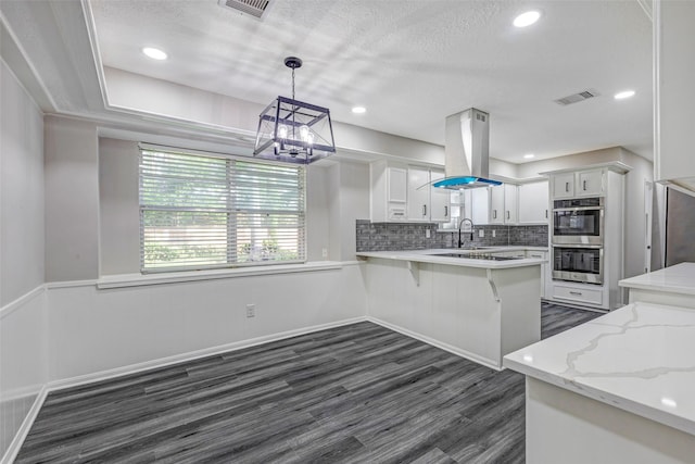 5206 Summerfield Ln, Spring, TX 77379 - kitchen with island range hood, double oven, a chandelier, dark wood-type flooring, and white cabinetry