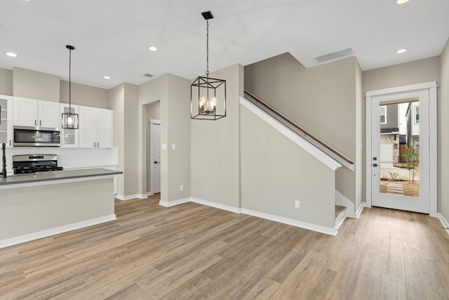 416 Stonework Landing Ln, Houston, TX 77076 - kitchen with appliances with stainless steel finishes, light wood finished floors, a chandelier, decorative light fixtures, and white cabinetry