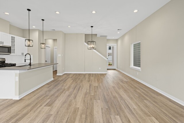 416 Stonework Landing Ln, Houston, TX 77076 - kitchen with stainless steel microwave, gas stove, light wood finished floors, white cabinets, and recessed lighting