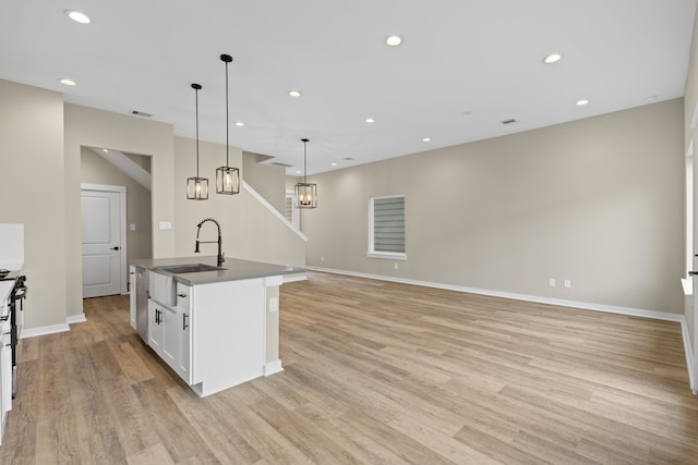 416 Stonework Landing Ln, Houston, TX 77076 - kitchen featuring light wood-type flooring, a center island with sink, white cabinets, recessed lighting, and decorative light fixtures