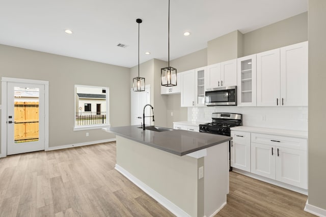 416 Stonework Landing Ln, Houston, TX 77076 - kitchen featuring stainless steel appliances, light wood-style flooring, backsplash, white cabinetry, and glass insert cabinets