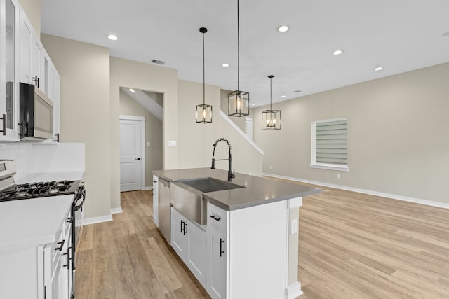 416 Stonework Landing Ln, Houston, TX 77076 - kitchen with stainless steel appliances, light wood-style flooring, recessed lighting, a center island with sink, and white cabinets