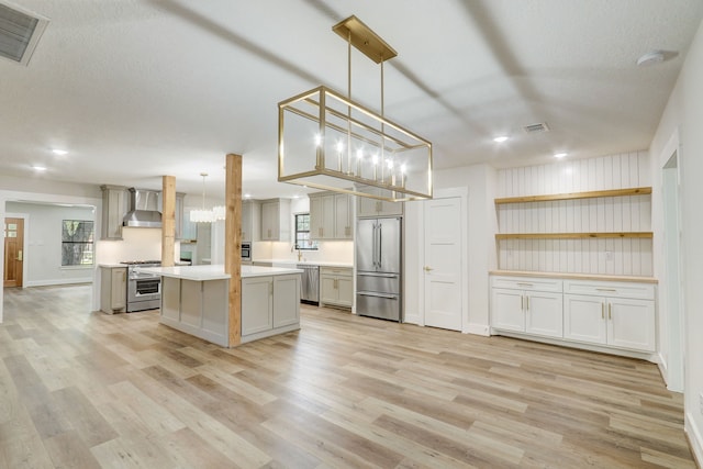 707 N Main St, Dayton, TX 77535 - kitchen with stainless steel appliances, wall chimney range hood, light countertops, a chandelier, and light wood finished floors