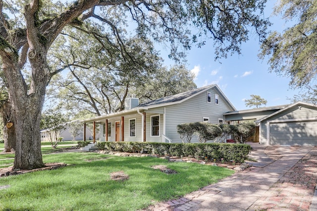 707 N Main St, Dayton, TX 77535 - view of front of home with a chimney, covered porch, driveway, a front lawn, and a garage