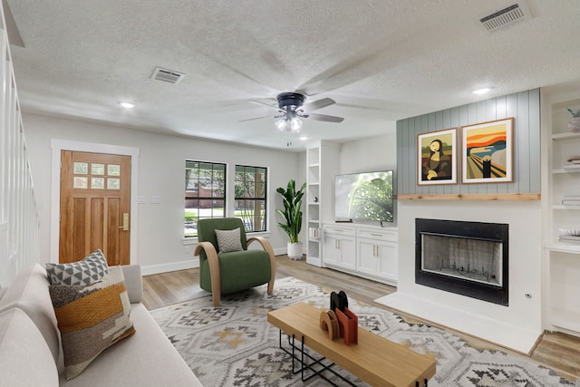 707 N Main St, Dayton, TX 77535 - living room with a ceiling fan, a textured ceiling, light wood-style flooring, a fireplace with flush hearth, and recessed lighting