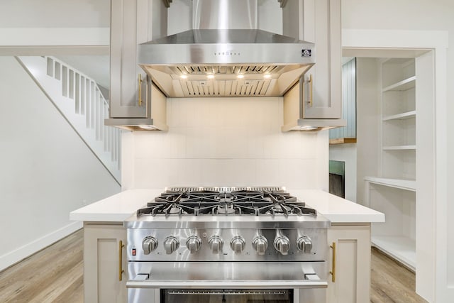 707 N Main St, Dayton, TX 77535 - kitchen featuring wall chimney range hood, stainless steel gas stove, light wood-type flooring, and light countertops