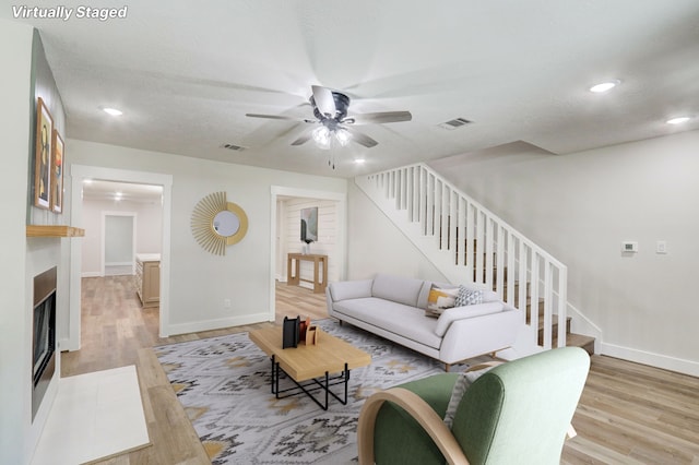 707 N Main St, Dayton, TX 77535 - living room featuring stairway, light wood-type flooring, recessed lighting, a ceiling fan, and a fireplace