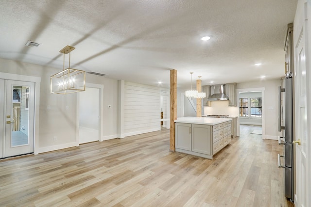 707 N Main St, Dayton, TX 77535 - kitchen with a chandelier, wall chimney range hood, a textured ceiling, light wood-type flooring, and light countertops