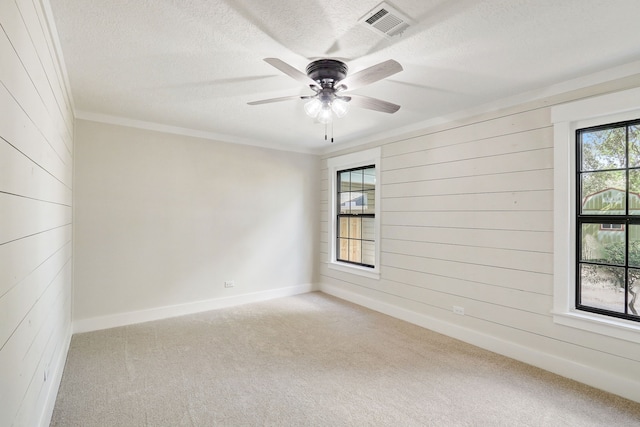 707 N Main St, Dayton, TX 77535 - carpeted empty room with a textured ceiling, wood walls, a ceiling fan, crown molding, and baseboards