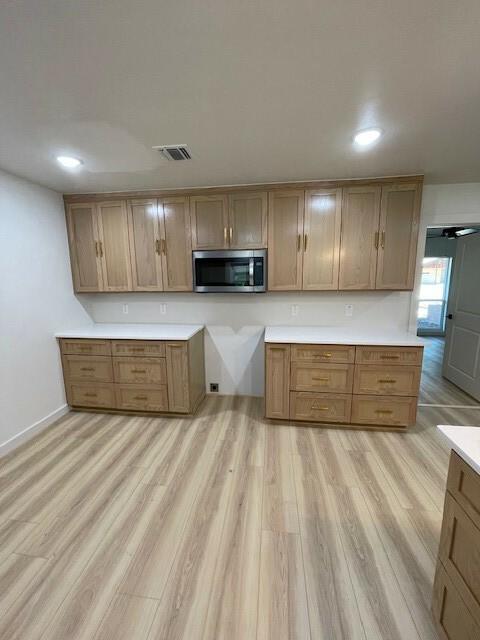 1221 N Hamilton St, Gonzales, TX 78629 - kitchen featuring stainless steel microwave, light wood-style flooring, light countertops, recessed lighting, and brown cabinetry