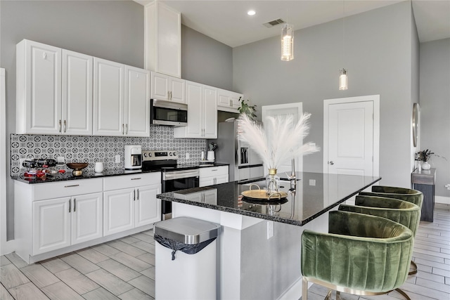 108 Bianca Cir, Del Valle, TX 78617 - kitchen with stainless steel appliances, a towering ceiling, tasteful backsplash, white cabinets, and a breakfast bar