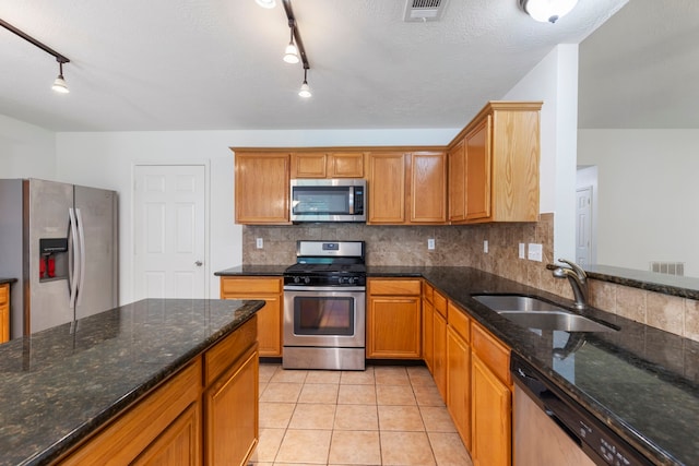 7023 Hayden Dr, Magnolia, TX 77354 - kitchen with appliances with stainless steel finishes, rail lighting, tasteful backsplash, and light tile patterned floors