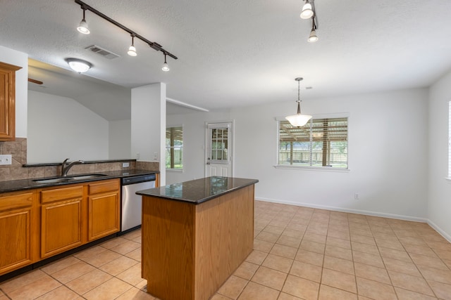 7023 Hayden Dr, Magnolia, TX 77354 - kitchen featuring dishwasher, rail lighting, plenty of natural light, light tile patterned flooring, and a textured ceiling