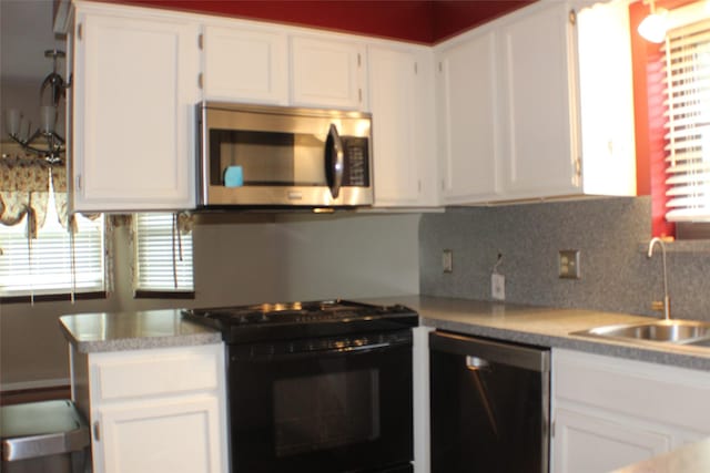 1408 Brandon Ct, Bay City, TX 77414 - kitchen featuring stainless steel microwave, black gas range oven, dishwashing machine, white cabinetry, and light countertops
