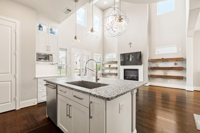 7714 S Fall Run Xing, Houston, TX 77055 - kitchen featuring a high ceiling, white cabinets, dark wood-type flooring, light stone counters, and an island with sink