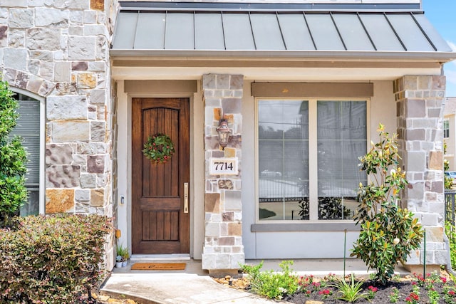 7714 S Fall Run Xing, Houston, TX 77055 - view of exterior entry featuring a standing seam roof, stone siding, and a metal roof