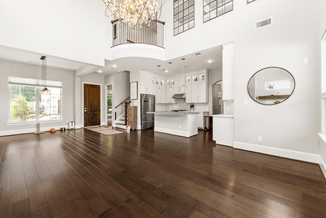 7714 S Fall Run Xing, Houston, TX 77055 - unfurnished living room with a chandelier, stairs, dark wood-type flooring, and a high ceiling
