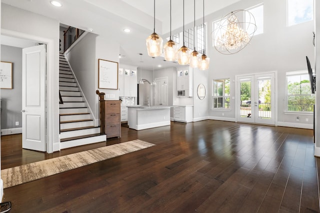 7714 S Fall Run Xing, Houston, TX 77055 - unfurnished living room featuring dark wood-style flooring, stairs, recessed lighting, a chandelier, and a high ceiling