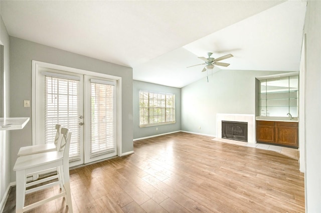 14600 Fonmeadow Dr Unit 201, Houston, TX 77035 - unfurnished living room with a ceiling fan, a tiled fireplace, vaulted ceiling, and light wood-style flooring