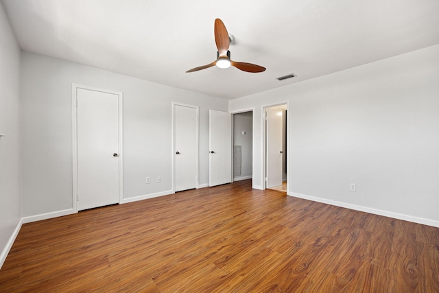 10328 Longmont Dr Unit 47/1, Houston, TX 77042 - unfurnished bedroom featuring multiple closets, wood finished floors, and ceiling fan