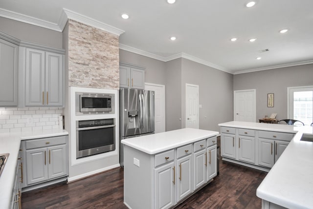 2808 Apache St, League City, TX 77573 - kitchen with stainless steel appliances, gray cabinets, dark wood-style flooring, a center island, and crown molding