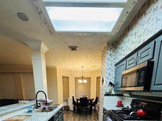 1631 Almond Brook Ln, Houston, TX 77062 - kitchen featuring range, stainless steel microwave, wallpapered walls, wood finished floors, and a chandelier