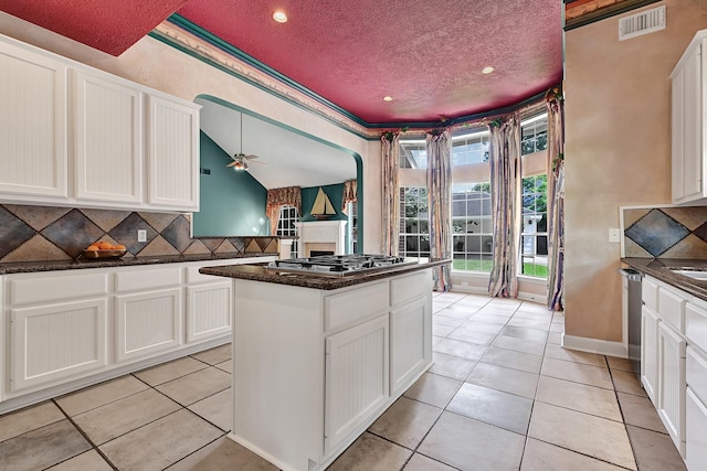 6102 Walkers Park Dr, Sugar Land, TX 77479 - kitchen featuring stainless steel gas stovetop, tasteful backsplash, light tile patterned floors, a textured ceiling, and a center island