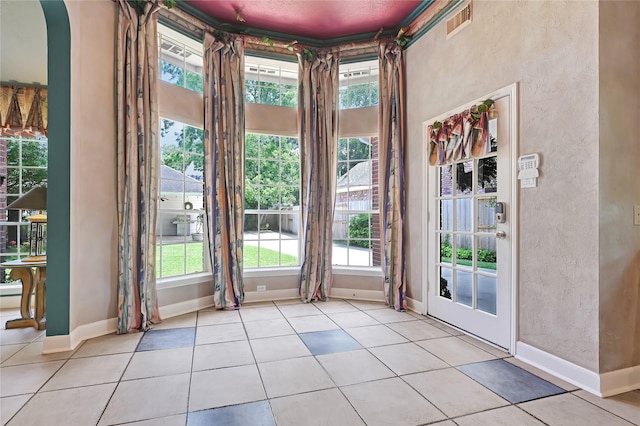 6102 Walkers Park Dr, Sugar Land, TX 77479 - doorway with plenty of natural light, a textured wall, light tile patterned flooring, and arched walkways