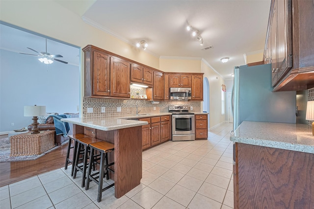 13820 Midway Dr, Willis, TX 77318 - kitchen with stainless steel appliances, light tile patterned floors, a peninsula, ceiling fan, and ornamental molding