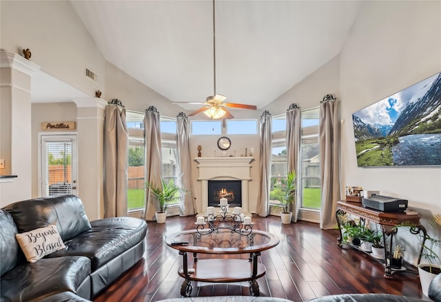 3318 Legends Mist Dr, Spring, TX 77386 - living room featuring a warm lit fireplace, high vaulted ceiling, ceiling fan, dark wood-style floors, and ornate columns