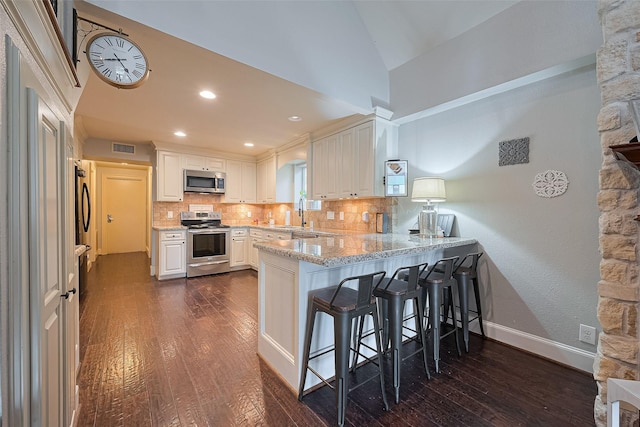 152 Snug Harbor Dr, Conroe, TX 77356 - kitchen with appliances with stainless steel finishes, dark wood-style floors, a peninsula, backsplash, and vaulted ceiling