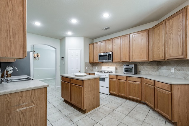 16311 Sylvan Dale Dr, Humble, TX 77346 - kitchen featuring white range with gas cooktop, stainless steel microwave, backsplash, arched walkways, and light countertops