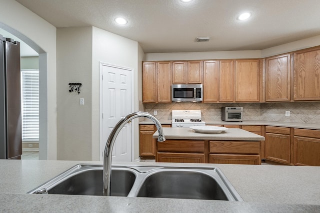 16311 Sylvan Dale Dr, Humble, TX 77346 - kitchen with appliances with stainless steel finishes, arched walkways, tasteful backsplash, light countertops, and recessed lighting