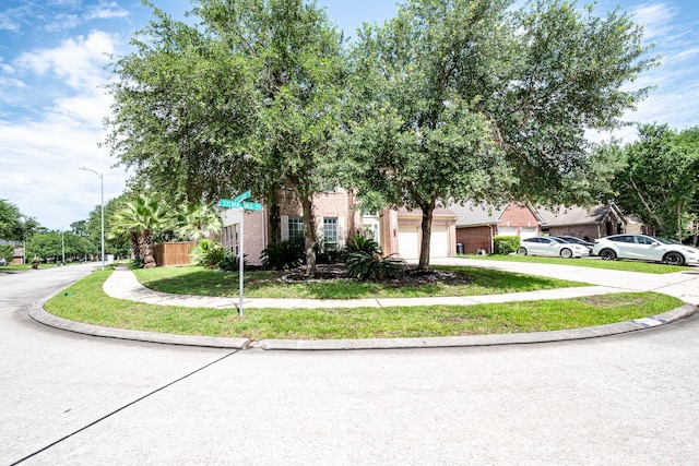 16311 Sylvan Dale Dr, Humble, TX 77346 - view of property hidden behind natural elements with driveway, an attached garage, and a front yard