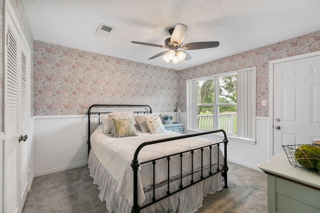 7310 Blenheim Palace Ln, Houston, TX 77095 - carpeted bedroom with wallpapered walls, a wainscoted wall, a textured ceiling, and ceiling fan