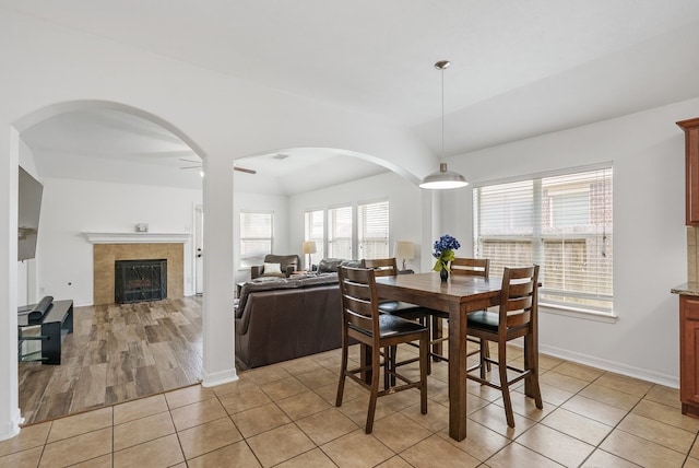 20930 Morgan Knoll Ln, Katy, TX 77449 - dining room with lofted ceiling, light tile patterned floors, arched walkways, and a fireplace