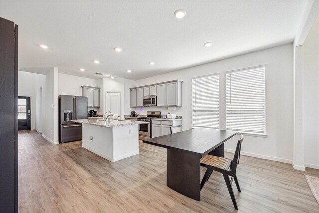 7227 Songlark Landing Ct, Katy, TX 77493 - kitchen featuring stainless steel appliances, gray cabinetry, recessed lighting, a center island with sink, and light stone countertops