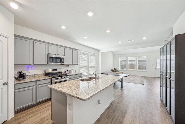 7227 Songlark Landing Ct, Katy, TX 77493 - kitchen with stainless steel appliances, gray cabinetry, an island with sink, light wood-style flooring, and recessed lighting