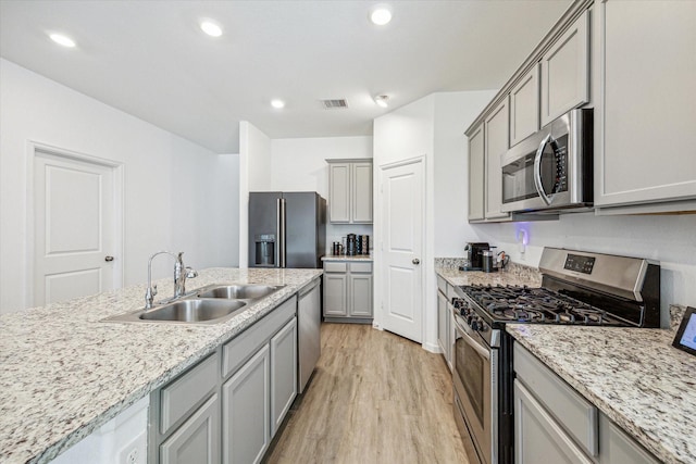 7227 Songlark Landing Ct, Katy, TX 77493 - kitchen with stainless steel appliances, gray cabinetry, light wood finished floors, recessed lighting, and light stone counters