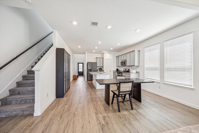7227 Songlark Landing Ct, Katy, TX 77493 - kitchen with stainless steel appliances, an island with sink, gray cabinets, light wood-style flooring, and healthy amount of natural light