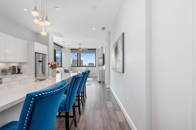 1211 Caroline St Unit 1504, Houston, TX 77002 - kitchen with freestanding refrigerator, modern cabinets, a breakfast bar, white cabinetry, and hanging light fixtures