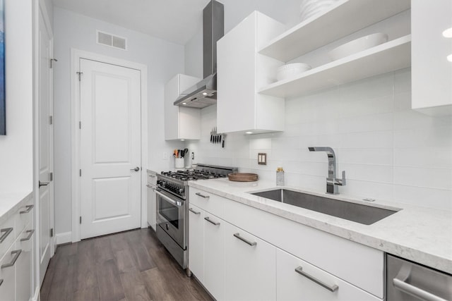 1211 Caroline St Unit 1504, Houston, TX 77002 - kitchen featuring appliances with stainless steel finishes, wall chimney exhaust hood, decorative backsplash, white cabinets, and light stone countertops