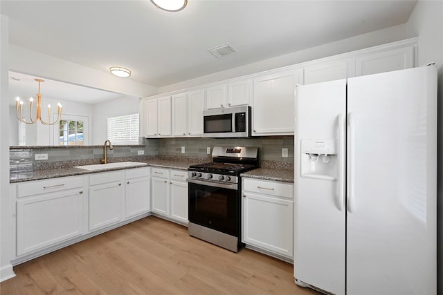 206 Delaney St, Houston, TX 77009 - kitchen with appliances with stainless steel finishes, light wood-type flooring, white cabinetry, and backsplash