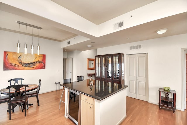 3505 Sage Rd Unit 2910, Houston, TX 77056 - kitchen featuring wine cooler, light wood-type flooring, dark countertops, a center island, and decorative light fixtures