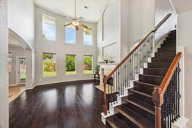 2332 Shadow Falls Ln, Pearland, TX 77584 - entrance foyer with a ceiling fan, a fireplace with flush hearth, arched walkways, a towering ceiling, and hardwood / wood-style flooring