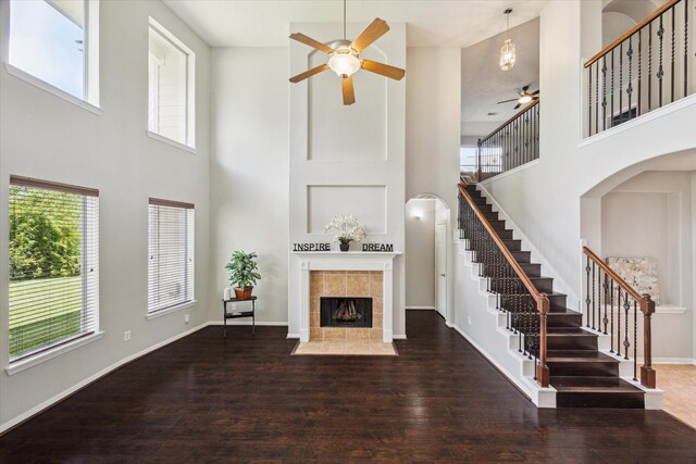 2332 Shadow Falls Ln, Pearland, TX 77584 - unfurnished living room featuring ceiling fan, a high ceiling, a tiled fireplace, stairs, and healthy amount of natural light