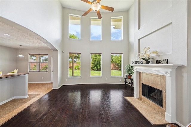 2332 Shadow Falls Ln, Pearland, TX 77584 - unfurnished living room with a fireplace, ceiling fan, arched walkways, wood-type flooring, and a high ceiling