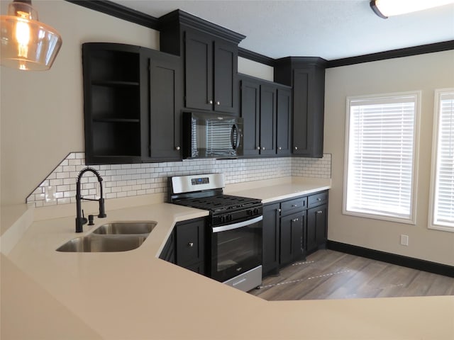 11918 Sagedowne Ln, Houston, TX 77089 - kitchen featuring black microwave, stainless steel range with gas stovetop, light wood-style flooring, ornamental molding, and decorative backsplash